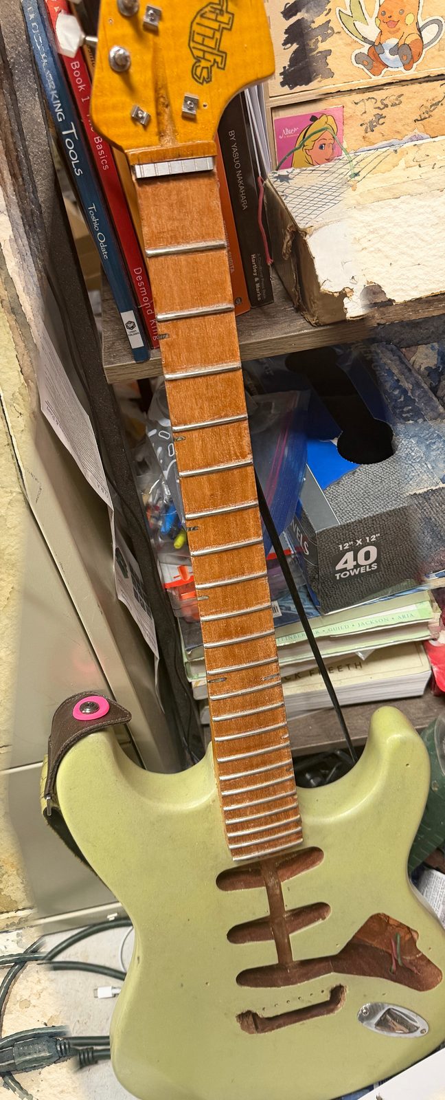 Seafoam learner-kit body and maple neck on the bench. Workshop photo, painted ground.